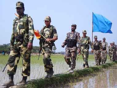 Border Security Force (L, with orange flag) and Bangladesh Rifles troopers (R, with blue flag) conduct a joint foot patrol on the zero line, the India-Bangladesh border, in Nischintapur. AFP