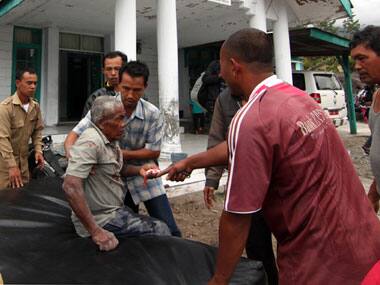 Acenese men assist an earthquake victim to receive medical treatment outside a community health center in Bener Meriah, Aceh province, Indonesia. AP