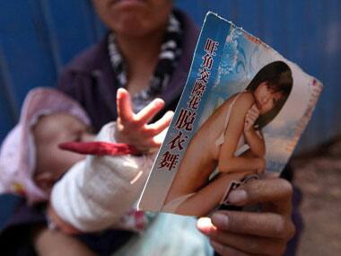 A Chinese woman sells pornographic CDs. AFP.