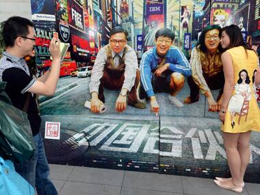 People take pictures with an advertisement board of the movie 