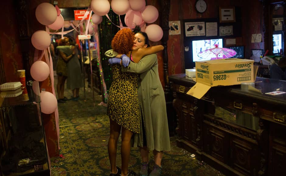 An exotic dancer (L) embraces a fellow employee at the Lusty Lady strip club in San Francisco, California September 2, 2013. United States' first and only unionized, employee-owned strip club shuts its doors on September 2 after its landlord refused to negotiate on a lower rent, local media reported. REUTERS/Stephen Lam