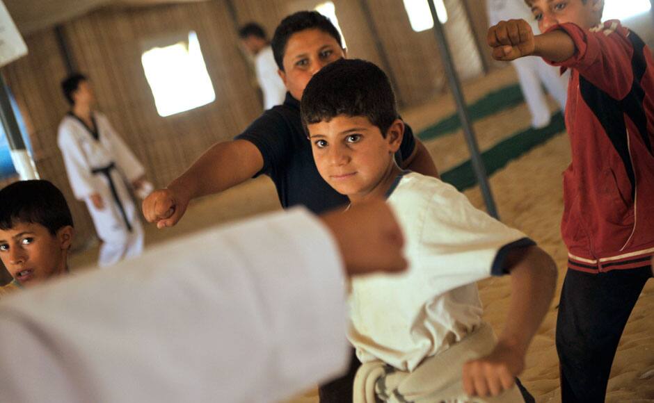 Syrian refugee children look at their Korean Taekwondo instructor during training at Zaatari refugee camp, near Mafraq, Jordan. AP Photo/Bela Szandelszky. 