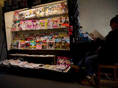 A vendor reads next to her newspaper and magazine stand in London, Wednesday, Oct. 30, 2013. Britain's press is going to court in a bid to stop the imposition of new rules developed after the country's phone hacking scandal. Officials are working to create a body which would subject Britain's newspapers and magazines to a government-backed watchdog insulated from media owners and publishers. AP