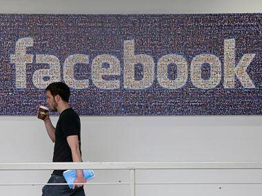  Facebook employee walks past a sign at Facebook headquarters in Menlo Park.  AP 