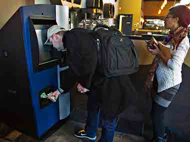 A customer puts money into the world's first ever permanent bitcoin ATM unveiled at a coffee shop in Vancouver. Reuters