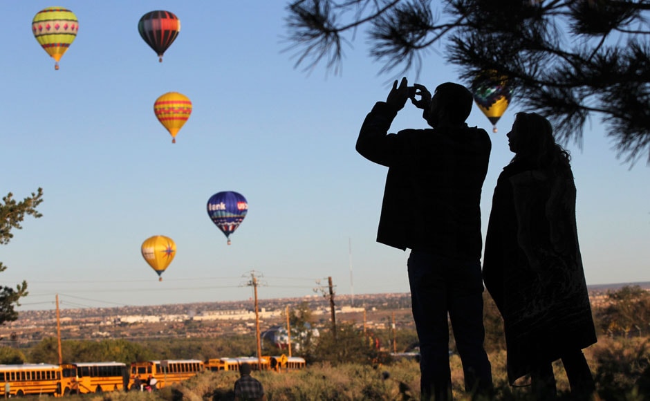 A visitor takes pictures of hot air balloons flying overhead: Reuters A visitor takes pictures of hot air balloons flying overhead: Reuters