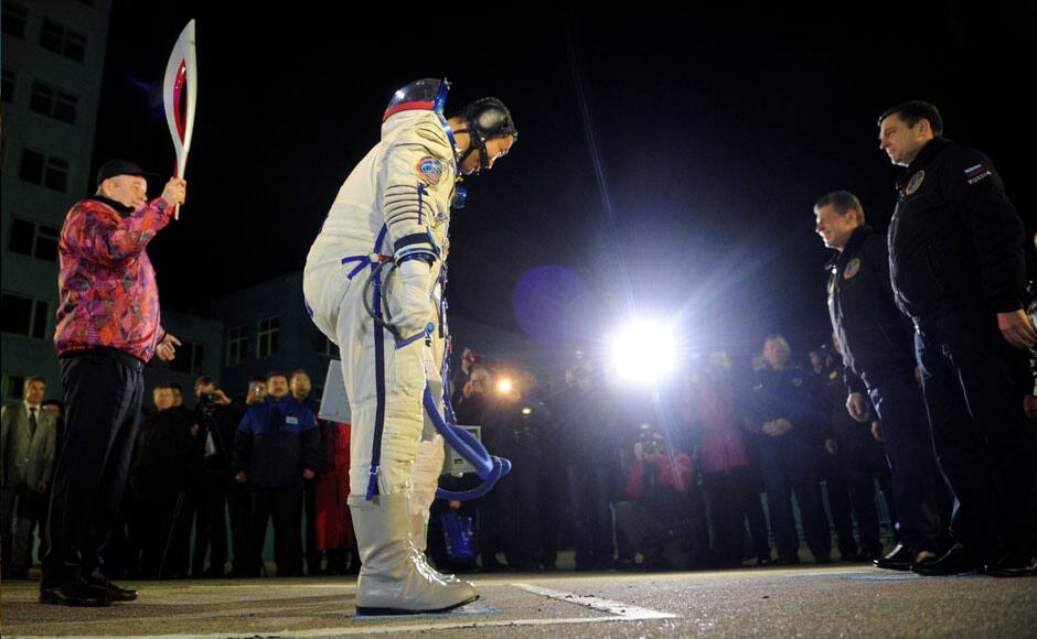 Russia's Roscosmos space agency chief Oleg Ostapenko (front R) greets crew members of the International Space Station (ISS) in front of a Roscosmos official carrying the torch of the 2014 Sochi Winter Olympic Games shortly before the crew members board the Soyuz TMA-11M spacecraft at the Baikonur cosmodrome November 7, 2013. REUTERS