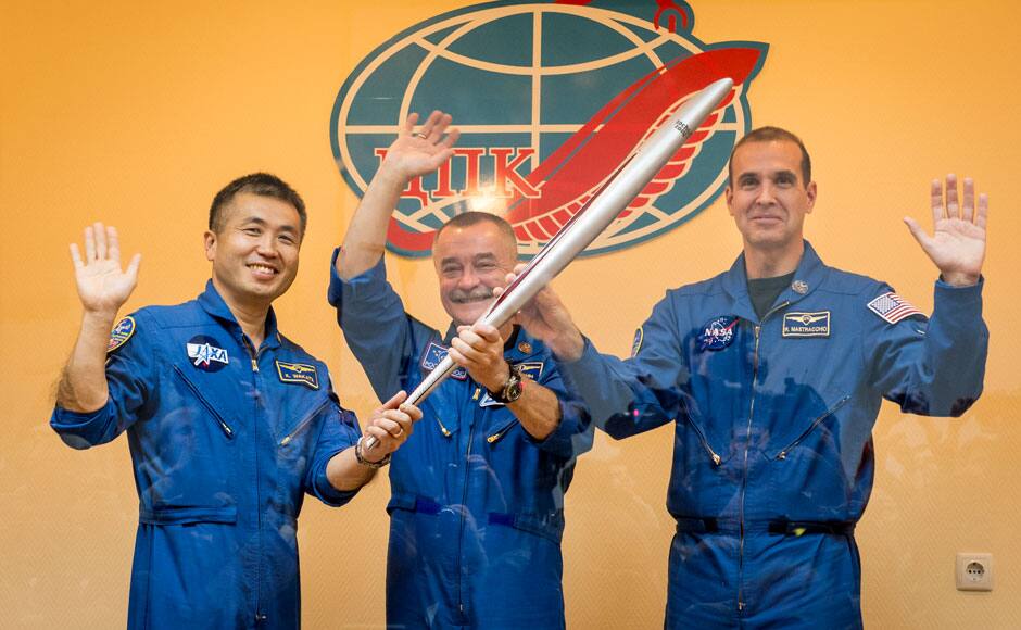 Expedition 38 Flight Engineer Koichi Wakata (L), of the Japan Aerospace Exploration Agency, Soyuz Commander Mikhail Tyurin (C), of Roscosmos, and Flight Engineer Rick Mastracchio of NASA smile as they hold an Olympic torch that will be flown with them to the International Space Station, during a press conference held at the Cosmonaut hotel in Baikonur November 6, 2013. The launch of the Soyuz rocket is scheduled for November 7 and will send Tyurin, Mastracchio and Wakata on a six-month mission aboard the International Space Station. REUTERS
