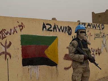 file photo, a United Nations peacekeeper stands guard at the entrance to the main polling station, covered in separatist flags and graffiti supporting the creation of the independent state of Azawad, in Kidal, Mali. Radio France Internationale’s senior correspondent Ghislaine Dupont, 57, and 55-year-old technician Claude Verlon had just finished interviewing a Tuareg rebel leader in Kidal on Saturday, Nov. 2, 2013, when they were grabbed at around 1 p.m. AP