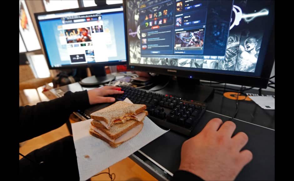 Millenium eSport professional gamer Arif of France, nicknamed Doigby, eats a sandwich in front of a computer screen as he plays inside the Millenium Gaming House in Marseille November 15, 2013. The Millenium Gaming House, which opened its doors in Marseille in 2011, is the most important French e-sport organization and houses pro gamers who live, game, eat and sleep full-time in the building. The house is dedicated to the training of Pro Gamers teams for International competitions. Players train long hours to master the difficulties and subtleties of only one game and participate in Lan-Parties around the world. E-Sports earnings has ranked the 100 players with the highest overall earnings from competitive gaming, with over 60 gamers who have earned over $100,000 in prize money. Picture taken November 15, 2013. REUTERS/Jean-Paul Pelissier 