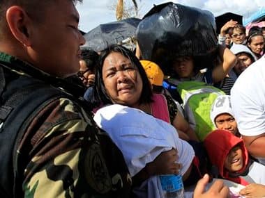 A woman and her child plead from the frantic crowd to be prioritized on an evacuation flight in Tacloban. AP
