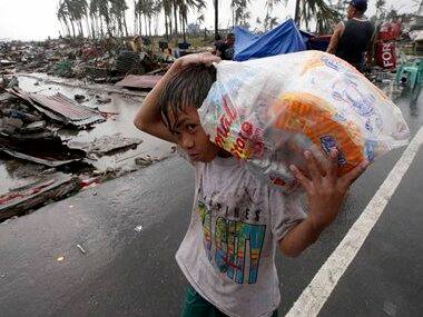 A boy carries relief goods, walking past the devastation caused by Typhoon Haiyan. AP