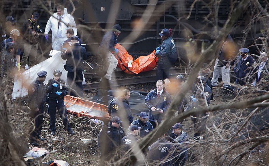 Officials remove a body from the scene of a Metro-North train derailment in the Bronx borough of New York December 1, 2013. At least four people were killed and 63 injured, including 11 critically, when the suburban train derailed, with at least five cars from the Metro-North train sliding off the tracks, officials said. REUTERS