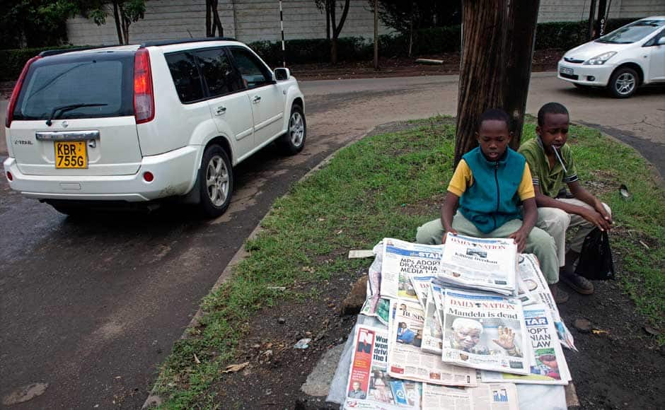Two young Kenyan boys sit near the pile morning newspapers on the street of Nairobi with the headlines of Nelson Mandela in Nairobi, Kenya, Friday, Dec. 6, 2013. Former South African President Nelson Mandela died Friday Morning at the age of 95. AP