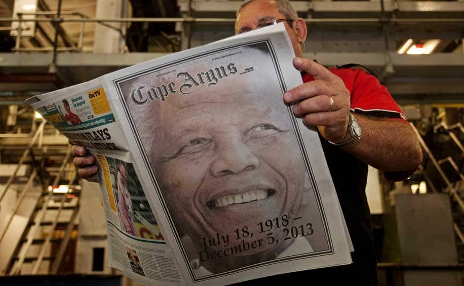 A man checks a copy of a recently printed newspaper paying tribute to former South African President Nelson Mandela at a printing press in the early hours of the morning in Cape Town December 6, 2013. South African anti-apartheid hero Mandela died peacefully at home at the age of 95 on Thursday after months fighting a lung infection, leaving his nation and the world in mourning for a man revered as a moral giant. REUTERS