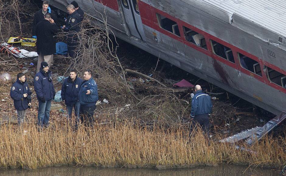 Emergency workers examine the site of a Metro North train derailment in the Bronx borough of New York December 1, 2013. A suburban New York train derailed on Sunday, killing four people and injuring 63, including 11 critically, when all seven cars of the Metro-North train ran off the tracks on a sharp curve, officials said. REUTERS