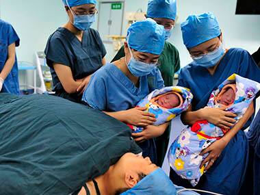 A Chinese nurse shows twins to their mother. Reuters