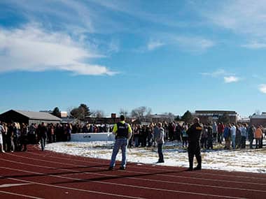 Sheriffs deputies stand guard over students after they were evacuated to the track and football field at Arapahoe High School in Centennial, Colo., on Friday, Dec. 13, 2013, where a student shot at least one other student at a Colorado high school Friday before he apparently killed himself, authorities said. The shooter entered Arapahoe High School in a Denver suburb armed with a shotgun and looking for a teacher he identified by name, said Arapahoe County Sheriff Grayson Robinson. AP