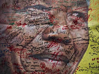 A poster of Nelson Mandela on which mourners have written their messages of condolence and support, in the street outside his old house in Soweto, Johannesburg, South Africa Friday, Dec. 6, 2013. Flags were lowered to half-staff and people in black townships, in upscale mostly white suburbs and in South Africa's vast rural grasslands commemorated Nelson Mandela with song, tears and prayers on Friday while pledging to adhere to the values of unity and democracy that he embodied. AP