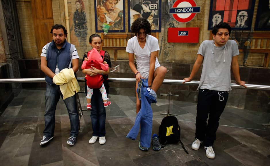 A man takes off his pants next to passengers at an underground platform during the 