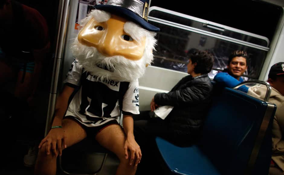 A man without pants and wearing a mask sits in a subway train during the 