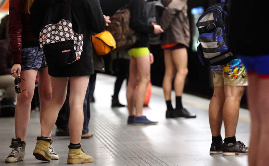 Passengers without their pants wait on a underground platform during the 