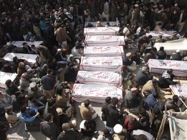 Shi'ite Muslims sit beside the covered bodies of victims who were killed in Tuesday night's bomb attack. Reuters