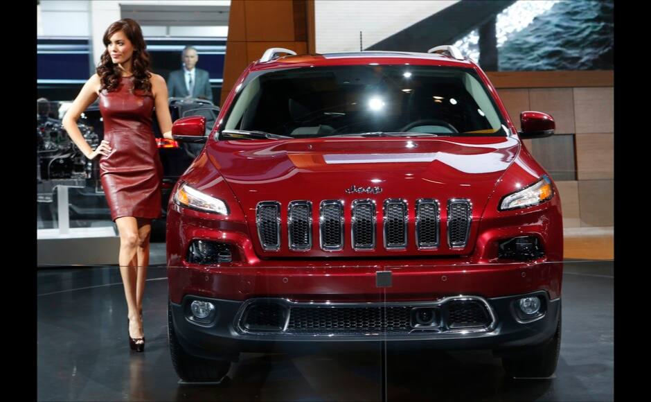 A model poses next to a Jeep Cherokee during the press preview day of the North American International Auto Show in Detroit, Michigan January 14, 2014. REUTERS