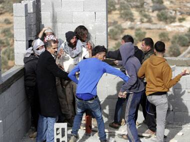 Palestinians try to keep others from further injuring Israeli settlers who are being detained by Palestinian villagers in a building under construction near the West Bank village of Qusra, southeast of Nablus. AP