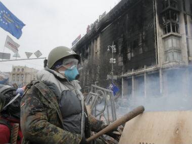 An anti-government protester stands behind a barricade during clashes with riot police in Kiev’s Independence Square in this file photo. AP