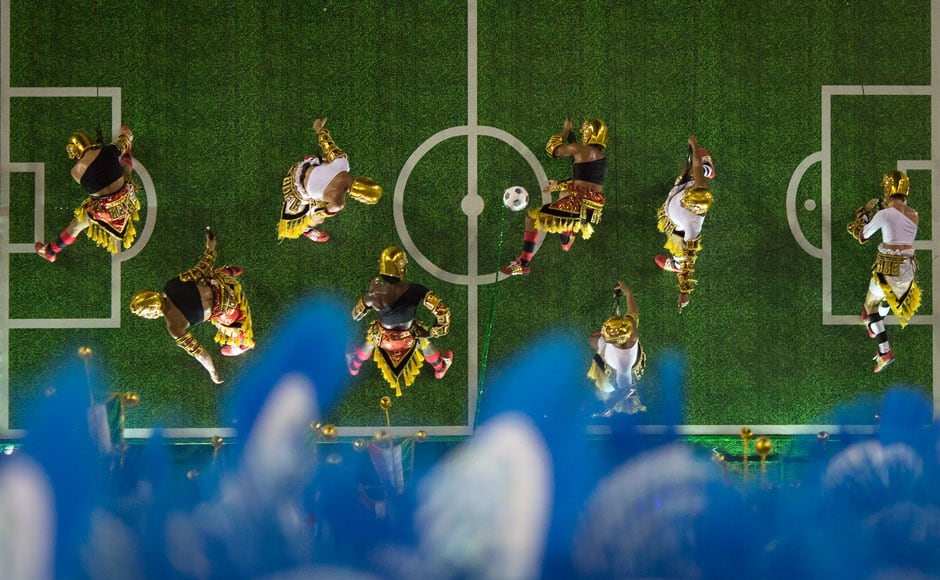Performers from the Imperatriz Leopoldinense samba school pretend to play soccer as they hang on the wall of a float during carnival celebrations at the Sambadrome in Rio de Janeiro, Tuesday, March 4, 2014. AP 