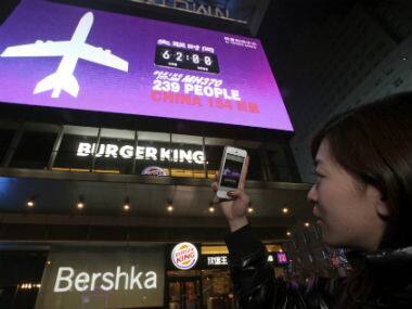  A woman taking a photo of a screen displaying the number of hours since a Malaysia Airlines passenger jet had gone missing at a mall in Beijing, China. AP 