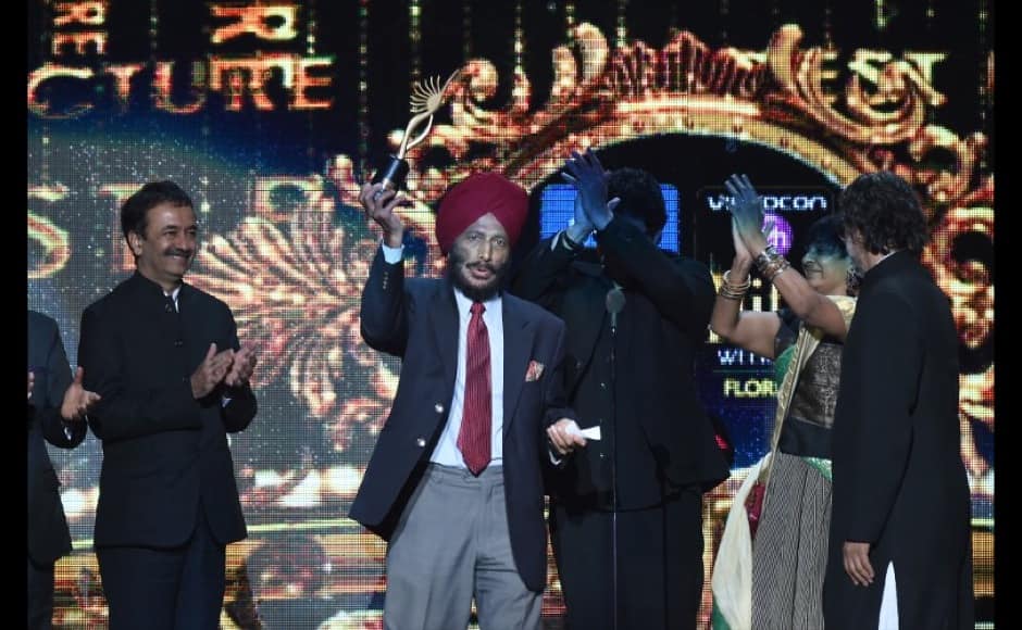 Bollywood director Rakeysh Omprakash Mehra (C-R) hands over the Best Picture trophy to Milkha Singh during the fourth and final day of the 15th International Indian Film Academy (IIFA) Awards at the Raymond James Stadium in Tampa, Florida, April 27, 2014. AFP PHOTO/Jewel Samad