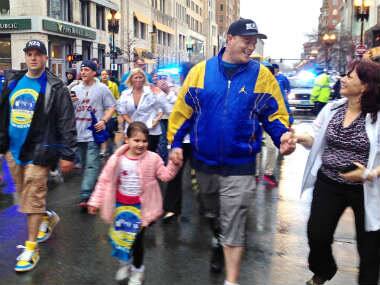 A woman greets Paul Norden, right, as he and his brother, J.P. Norden, left, walk with a group of family and friends down Boylston Street toward the Boston Marathon finish line in Boston, Tuesday, April 15, 2014. The brothers, each of whom lost his right leg in the 2013 Marathon bombings, traveled the 26.2 miles of the marathon route Tuesday as a fundraiser. AP