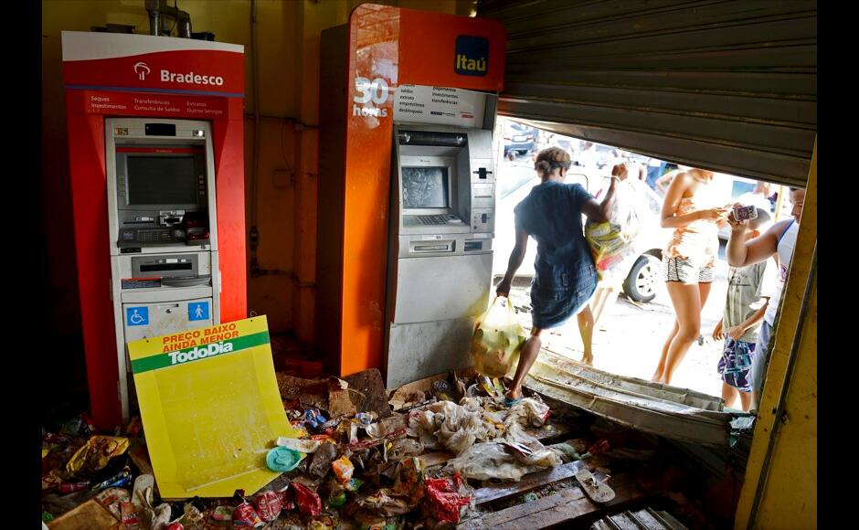 A woman carries bags of goods out of a supermarket that was looted during a police strike in Salvador, Bahia state, April 17, 2014. A police strike has unleashed violent crime in Brazil's third-largest city just two months before it is set to welcome hordes of soccer fans for the World Cup, adding to fears about the country's ability to ensure safety during the event. At least 22 people were killed in and around the northeastern city of Salvador after state police went on strike early on Wednesday to demand better pay and other benefits, the Bahia state government said on Thursday, prompting the federal government to dispatch troops to restore order. REUTERS