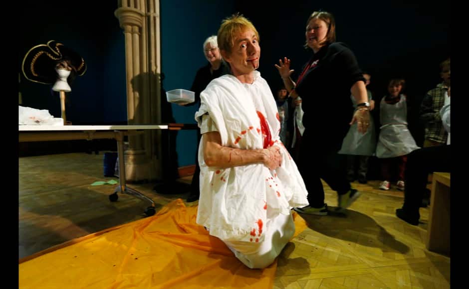 Volunteer Jonathan Cooksey, dressed as Julius Caesar, pretends to die after being stabbed with fake knives which concealed artificial blood during a workshop entitled 