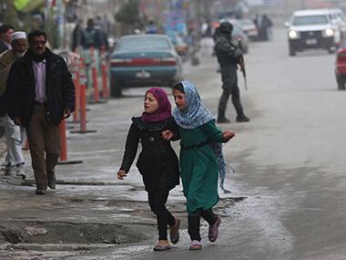 Afghan girls walk as a policeman, far right, stands guard in downtown Kabul, Afghanistan. AP