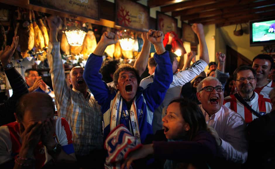 Real Madrid supporters celebrate player Sergio Ramos' goal during their Champions League final soccer match against Atletico Madrid, at a bar in Ronda, southern Spain, May 24, 2014. Real Madrid secured a 10th European Cup when they snatched a stoppage-time equaliser before extra-time goals by Gareth Bale, Marcelo and a Cristiano Ronaldo penalty gave them a 4-1 win over Atletico Madrid in the Champions League final in Lisbon on Saturday. REUTERS