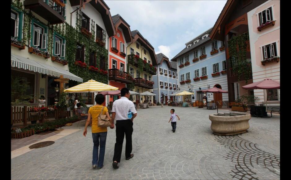A family walks in the Chinese replica of Austria's UNESCO heritage site, Hallstatt village, in China's southern city of Huizhou in Guangdong province June 1, 2012. Metals and mining company China Minmetals Corporation spent $940 million to build this controversial site and hopes to attract both tourists and property investors alike, according to local newspaper reports. REUTERS