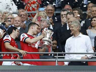 Arsenal’s club captain Thomas Vermaelen passes the trophy to coach Arsene Wenger. AP