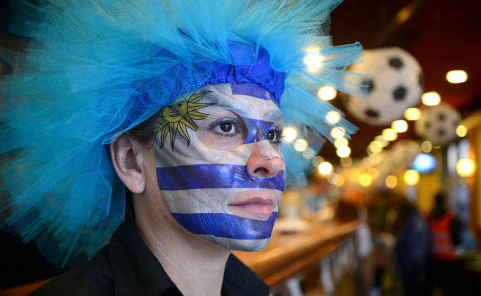 A soccer fan with a painted face in the colors of the Uruguayan national flag watches an open air broadcast of the 2014 World Cup Group D soccer match between Costa Rica and Uruguay, in Montevideo June 14, 2014. REUTERS