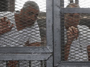 Al Jazeera journalists Mohammed Fahmy (L) and Peter Greste stand behind bars at a court in Cairo. Reuters image