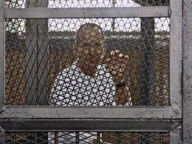 Al-Jazeera’s award-winning Australian correspondent Peter Greste appears in a defendants’ cage in the Police Academy courthouse along with several other defendants during a trial on terror charges in Cairo. AP 