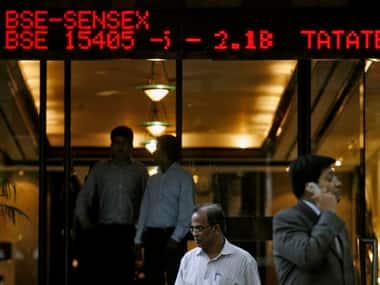 People walk past a digital screen displaying India's benchmark share index in Mumbai