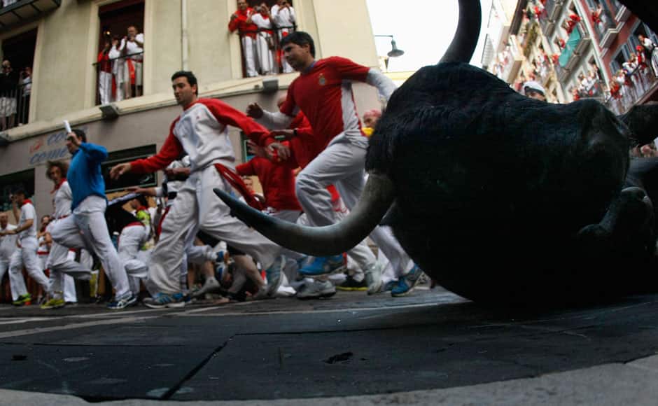 A Dolores Aguirre fighting bull falls at the Estafeta corner, during the second running of the bulls of the San Fermin festival in Pamplona July 8, 2014. Two runners were hospitalized following a run that lasted two minutes and twenty seconds, according to local media. REUTERS