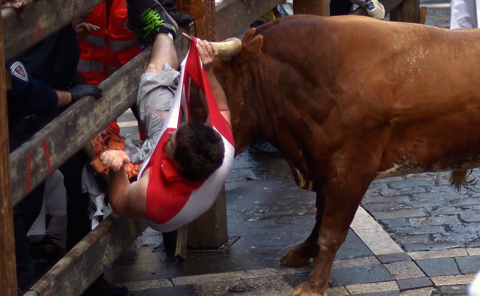 A runner is gored by a Miura fighting bull at Estafeta corner during the eighth running of the bulls of the San Fermin festival in Pamplona July 14, 2014. The festival, a heady mix of drinking, dancing, late nights and bullfights, made famous by Ernest Hemingway in his novel 