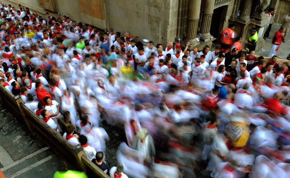 Runners move up the street before the first running of the bulls of the San Fermin festival in Pamplona July 7, 2014. Four people were hospitalised on Monday on the first day of Spain's San Fermin bull run, a daily race through the narrow, cobbled streets of Pamplona that forms part of the northern city's week-long festival. One runner was gored in the thigh while the other three suffered fractures during the race against five bulls which lasted 2 minutes and 25 seconds, according to the Red Cross. REUTERS