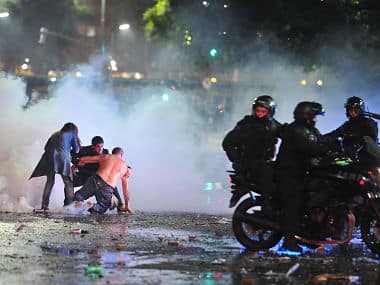 Soccer fans try to escape from a tear gas cloud and a police water cannon, used to restrain a group of youths who hurled rocks and vandalized stores. AP