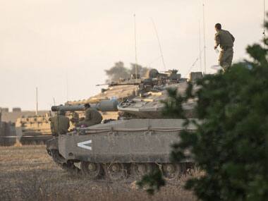 Israeli soldiers stand on Merkava tanks positioned on the Israeli side of the border with the Gaza Strip. AFP image