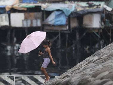 A Filipino girl walks under an umbrella in preparation for incoming Typhoon Rammasun. AP
